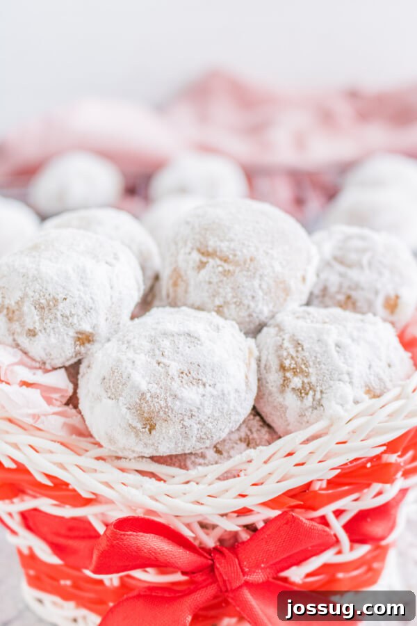 Finished Gingerbread Pecan Snowballs beautifully arranged and stacked in a charming holiday basket, ready for sharing as festive gifts.