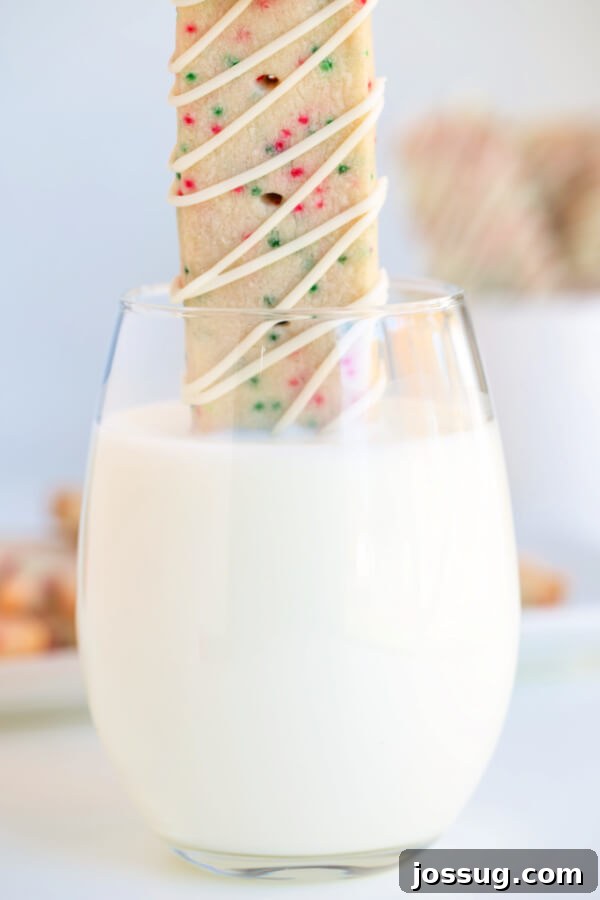 A shortbread cookie being dunked into a glass of cold milk, illustrating a perfect serving suggestion.