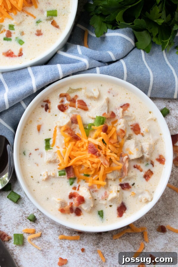 Creamy Chicken Bacon Ranch Delight 2 Creamy Chicken Bacon Ranch Soup in a bowl with a blue linen napkin, garnished with fresh parsley.