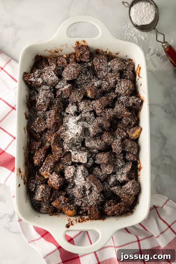 Decadent Chocolate Bread Pudding 2 A golden-brown pan filled with rich chocolate bread pudding, dusted lightly with powdered sugar, ready to be served.