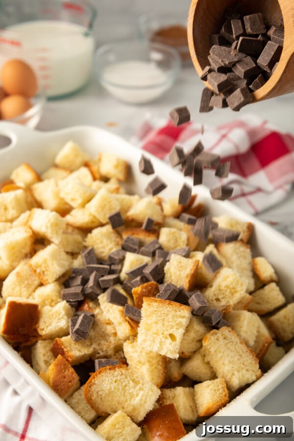 Decadent Chocolate Bread Pudding 4 Diced stale challah bread and a generous amount of semi-sweet chocolate chips are being combined in a large baking dish, ready for the custard mixture.