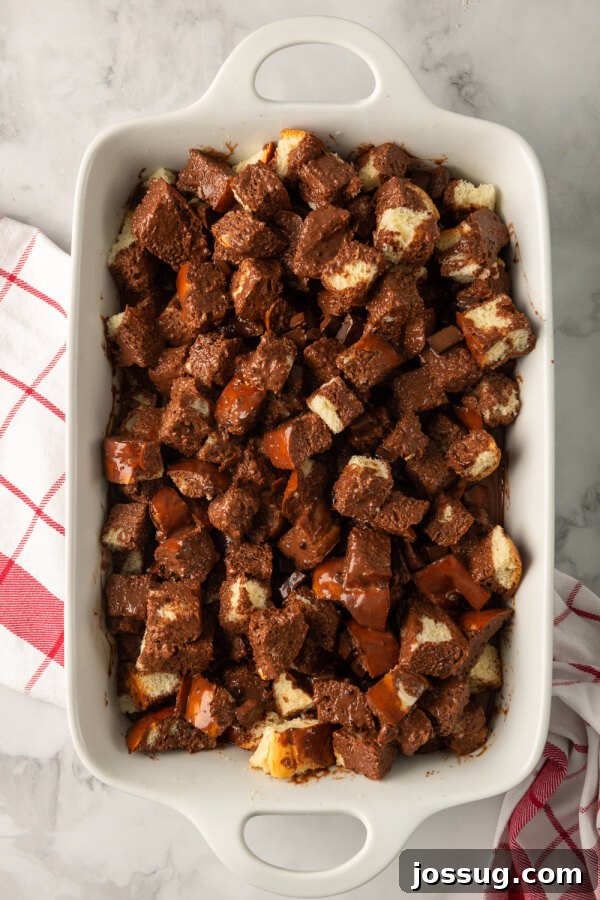 Decadent Chocolate Bread Pudding 7 The rich chocolate custard is being poured over the cubes of stale bread in a baking dish, ensuring thorough saturation before baking.
