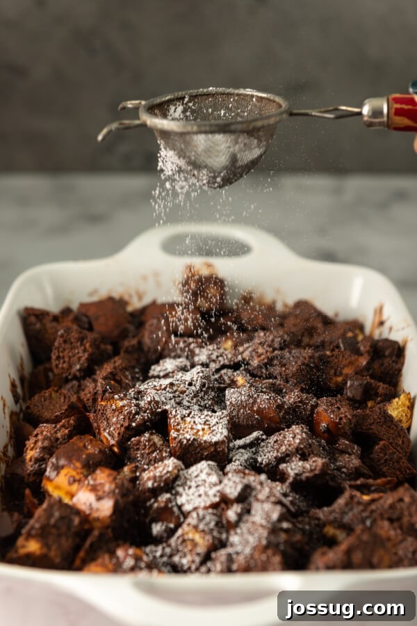 Decadent Chocolate Bread Pudding 8 A finished chocolate bread pudding, generously dusted with a delicate layer of powdered sugar, presented in a baking dish.