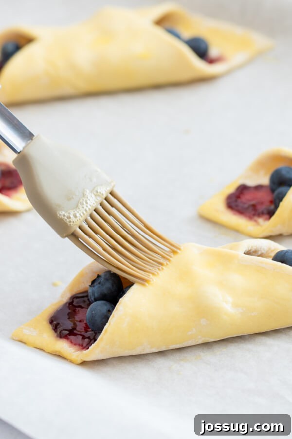 Bright Lemon Blueberry Danish Delight 7 The second fold of the Danish pastry, bringing the opposite corner over and brushing with egg wash to complete the shape