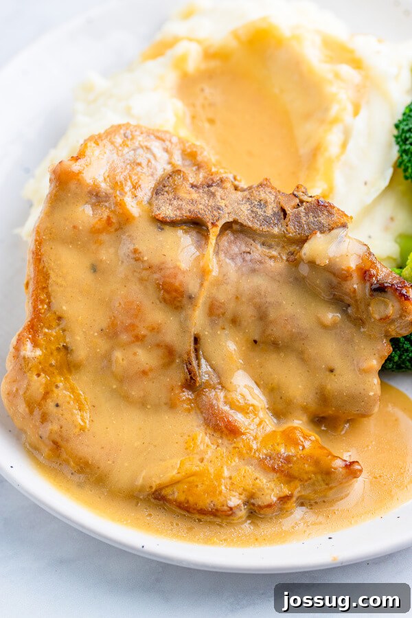 Tender Baked Pork Chops in Rich Pan Gravy 2 Perfectly baked pork chop with rich gravy served alongside fluffy mashed potatoes
