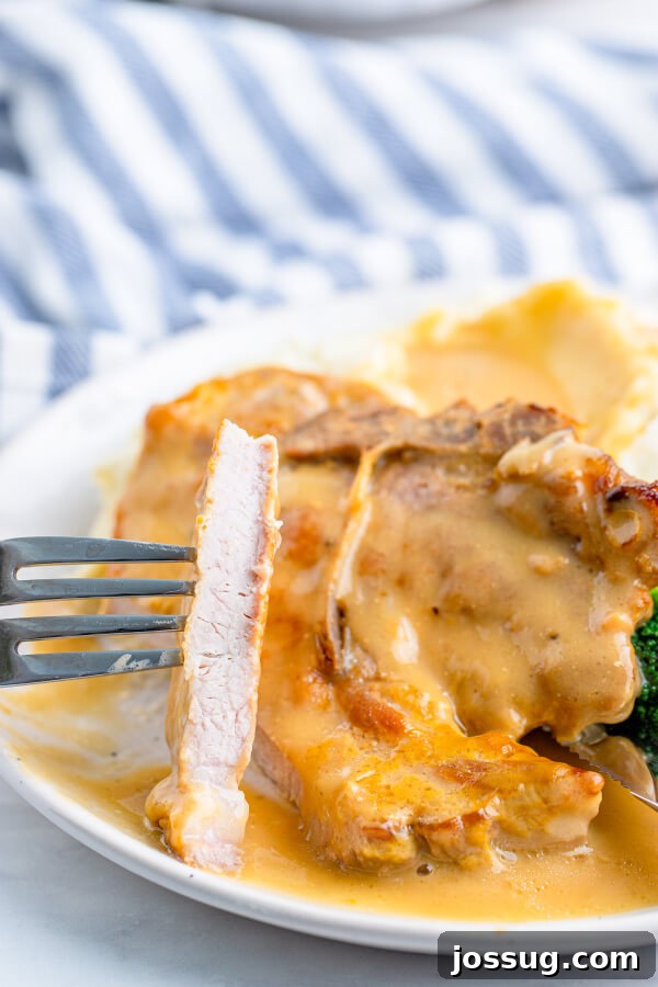 Tender Baked Pork Chops in Rich Pan Gravy 7 A finished baked pork chop cut open to show its tender, juicy interior, surrounded by rich gravy