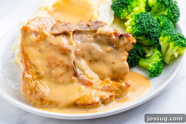 Tender Baked Pork Chops in Rich Pan Gravy 8 A beautifully plated baked pork chop with gravy, served with vibrant steamed broccoli