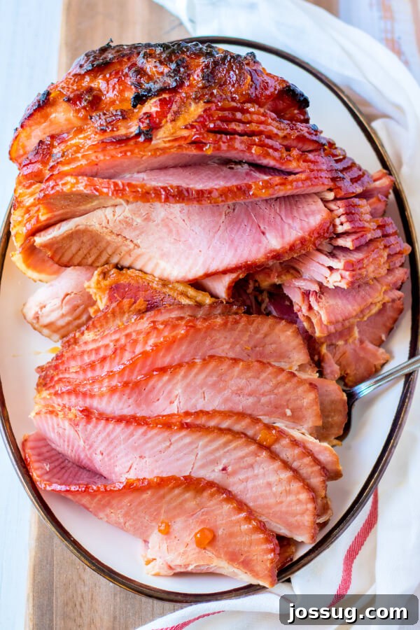 A beautifully glazed Apricot Dijon Spiral Ham on a platter, ready to be carved and served for a festive meal.