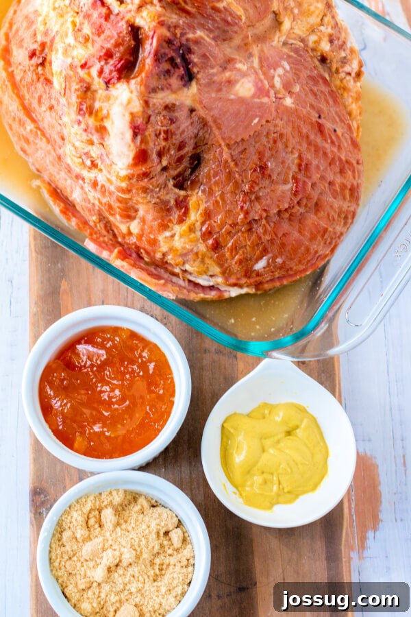 All the essential ingredients for the Apricot Dijon Spiral Ham laid out, including a whole spiral ham, brown sugar, apricot preserves, and Dijon mustard.