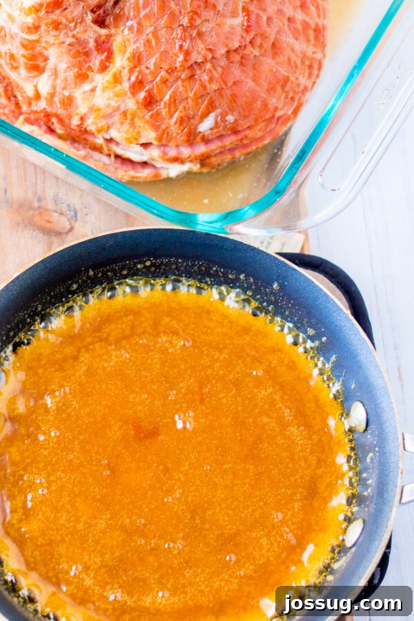 A small saucepan filled with the golden-brown apricot dijon glaze, perfectly simmered and ready to be brushed onto the spiral ham.
