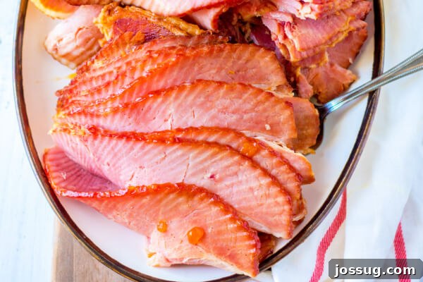 A single serving of cooked spiral ham on a white plate, showcasing its golden glaze and tender slices.