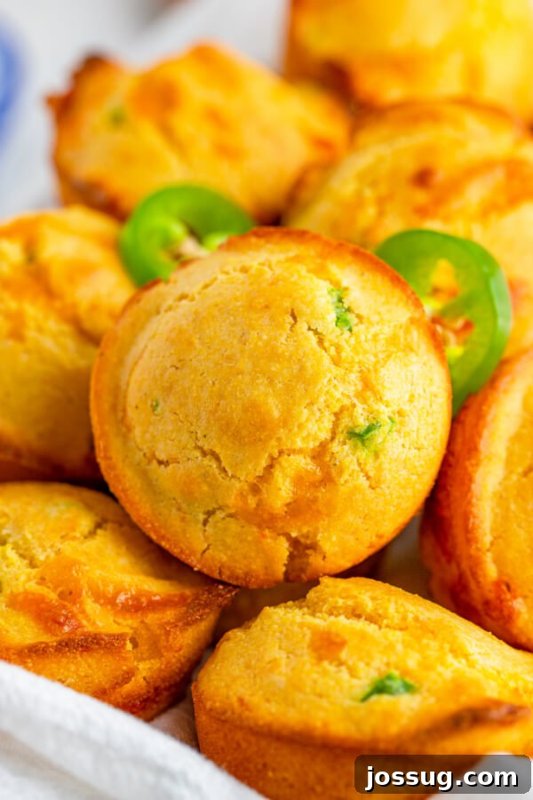 Golden-brown Jalapeño Cheddar Corn Muffins, fresh from the oven, with melted cheese visible on top.