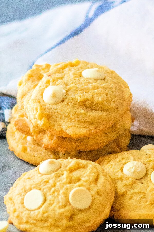 Bright Lemon Cloud Cookies 3 Three perfectly baked lemon pudding cookies, slightly cracked and golden, stacked on top of each other, showcasing their inviting chewiness and soft interior.