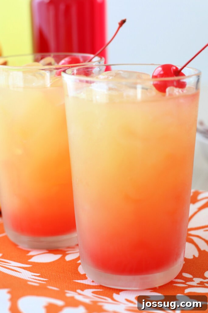Two vibrant Limoncello Sunrise cocktails garnished with orange slices and cherries, ready for a refreshing brunch.