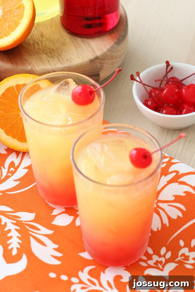 Looking down into two tall glasses of Limoncello Sunrise, showcasing the beautiful gradient of colors and garnishes.