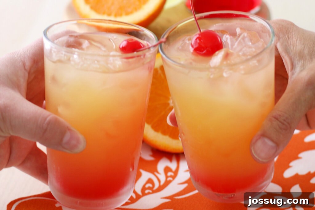 Two glasses of Limoncello Sunrise being clinked together in a toast, symbolizing celebration and enjoyment.