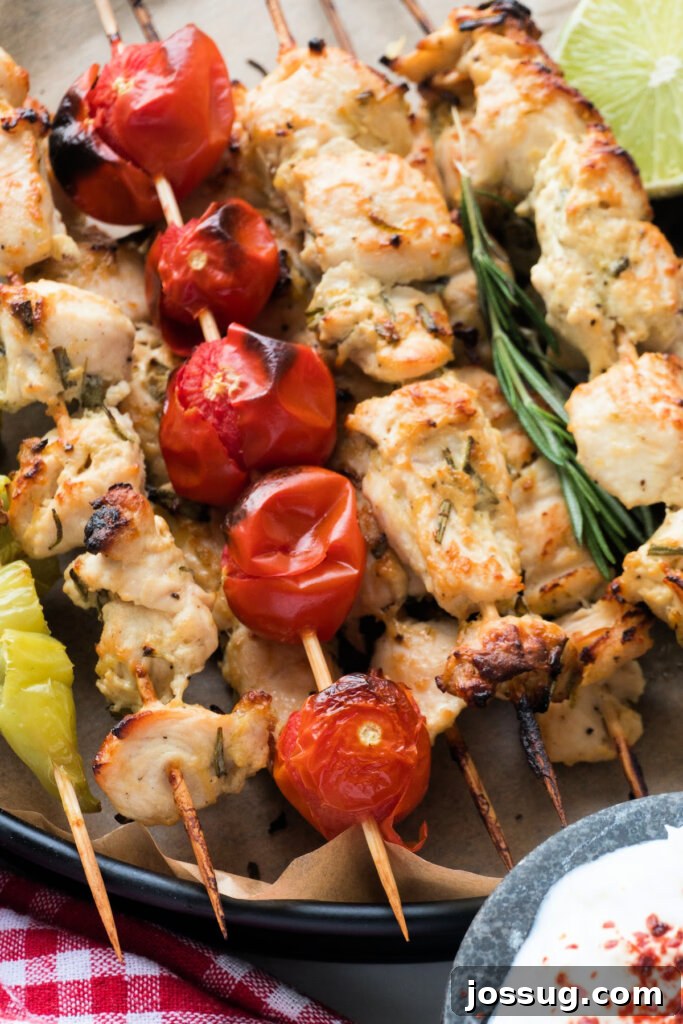 Stacked chicken skewers on a serving tray, garnished with fresh herbs.