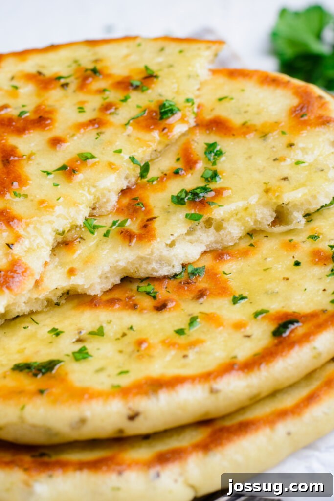 Handcrafted Dough Wonders 2 Stacked pieces of torn homemade flatbread, showing the fluffy interior, garnished with fresh herbs.