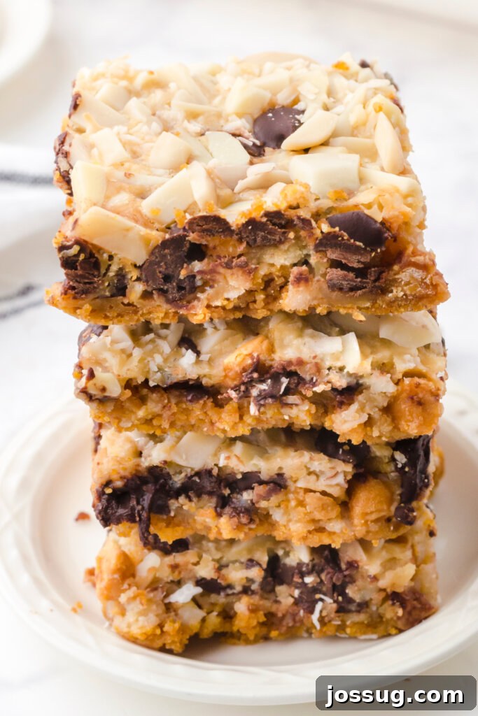 Miracle Layered Dessert Bars 2 Three Magic Cookie Bars stacked on a plate, showcasing their distinct layers of crust, chips, coconut, and nuts, with a golden-brown top.