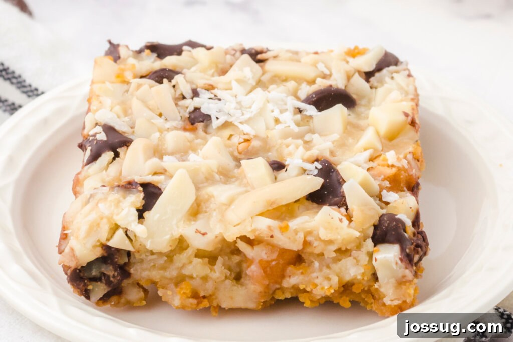 Miracle Layered Dessert Bars 5 A single Magic Cookie Bar served on a white plate, highlighting its rich, gooey center and crispy edges.