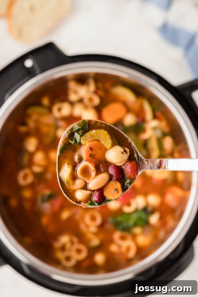 A ladle filled with savory Instant Pot Minestrone Soup, ready to be served from the Instant Pot.