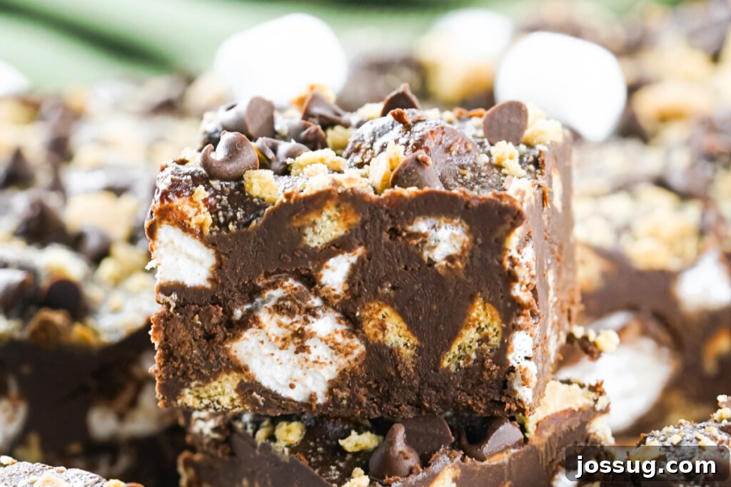 A S'mores Fudge square sitting on top of other pieces of fudge, highlighting its beautiful texture and irresistible appearance.