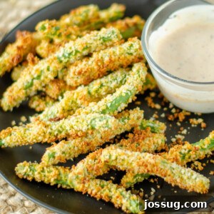 Crunchy Green Bean Frites 6 Green bean fries with dipping sauce on a black plate, with a fork