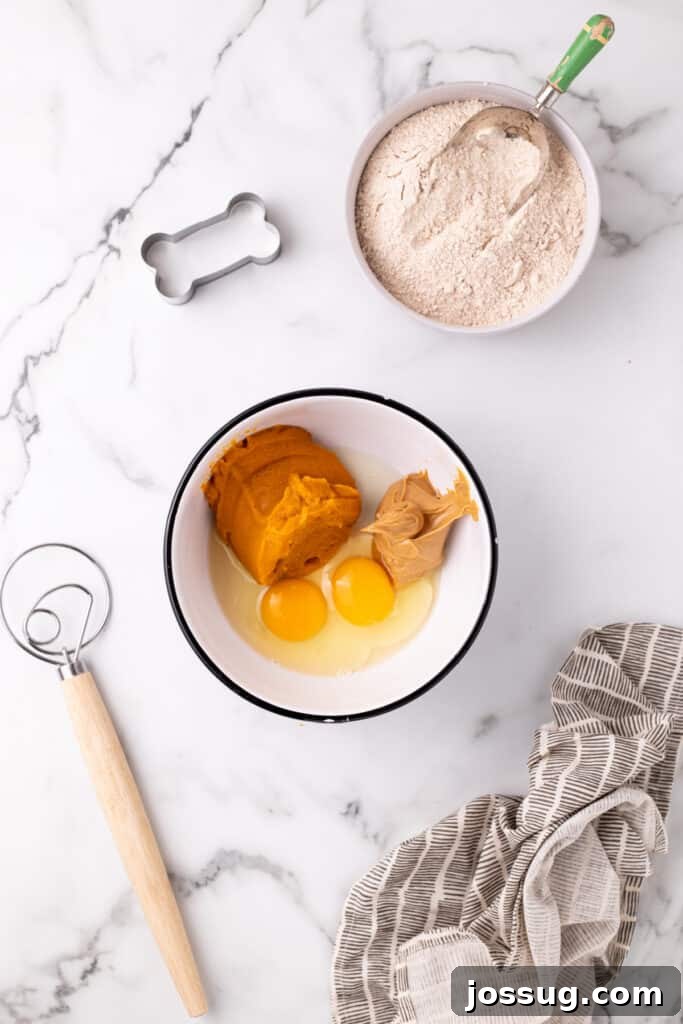 Pawsitively Delicious Air Fryer Treats 4 Initial mixing of pumpkin puree, fresh eggs, and creamy natural peanut butter in a pristine white mixing bowl, illustrating the first step in preparing the homemade dog treat dough.