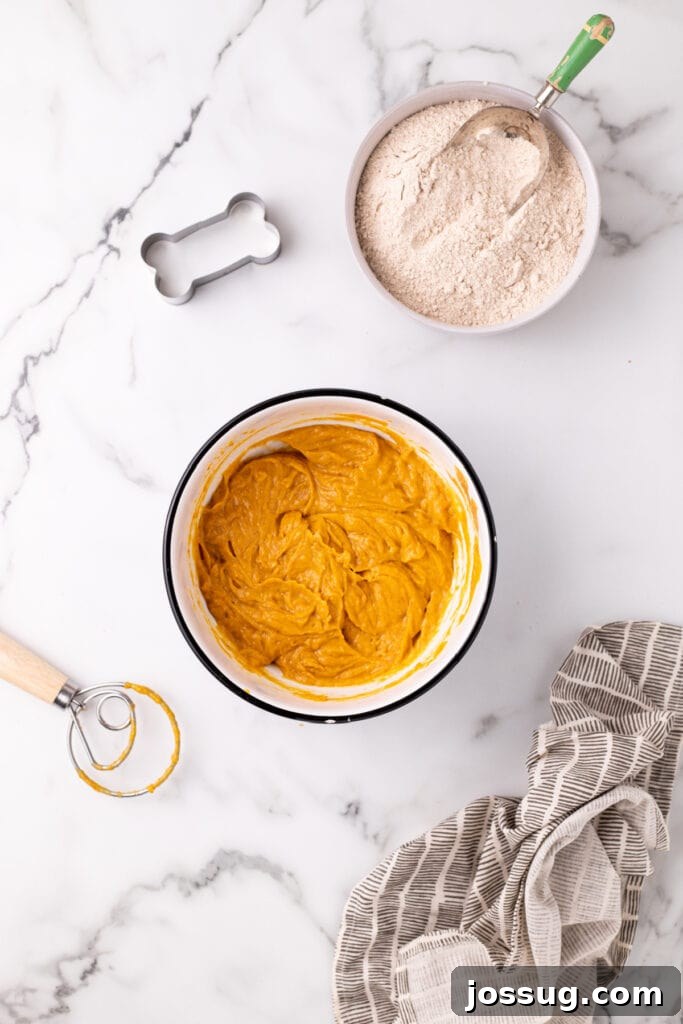 Pawsitively Delicious Air Fryer Treats 5 Smooth, well-combined mixture of pumpkin, peanut butter, and egg batter in a white bowl, showing the perfect consistency before the dry ingredients are incorporated.