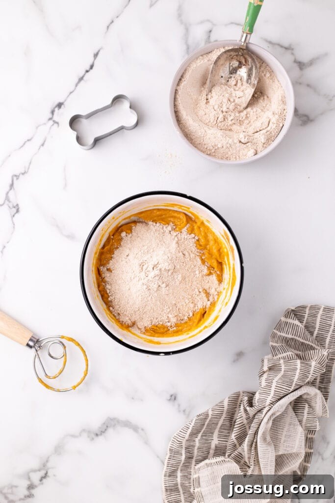 Pawsitively Delicious Air Fryer Treats 6 Whole wheat flour being gradually added to the wet pumpkin mixture, demonstrating the process of forming the homemade dog treat dough.