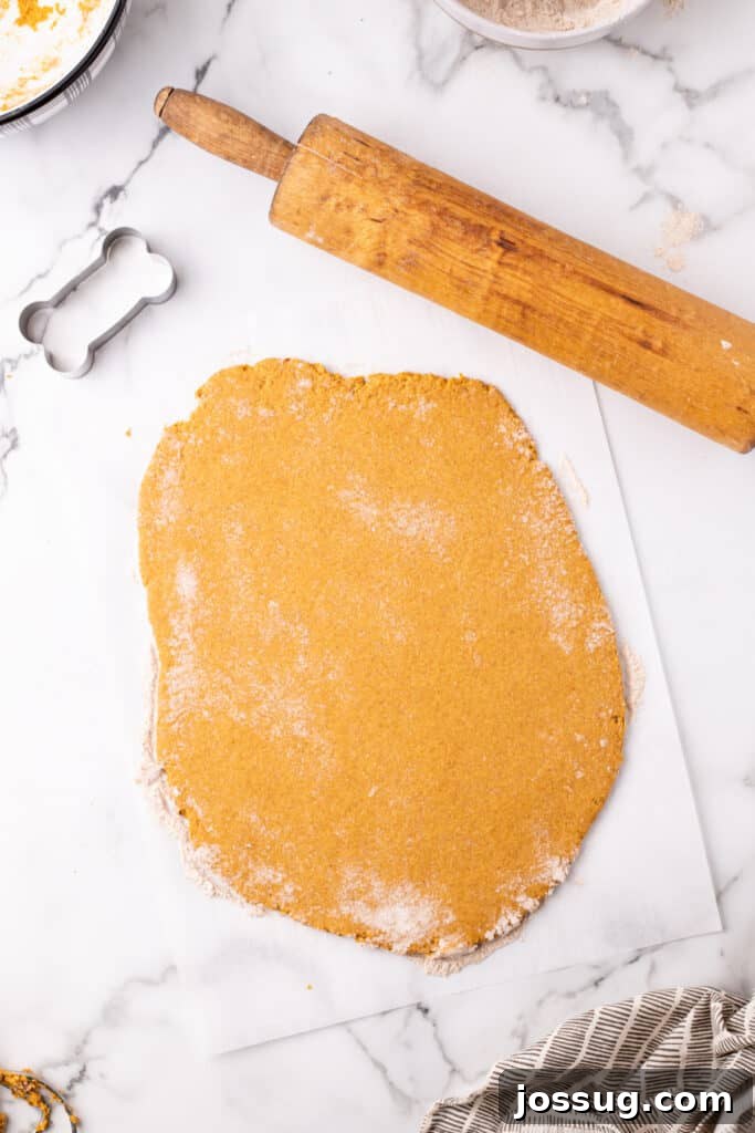 Pawsitively Delicious Air Fryer Treats 9 Evenly rolled out dog treat dough on parchment paper, showcasing the consistent thickness achieved with a vintage rolling pin, ready for cutting.
