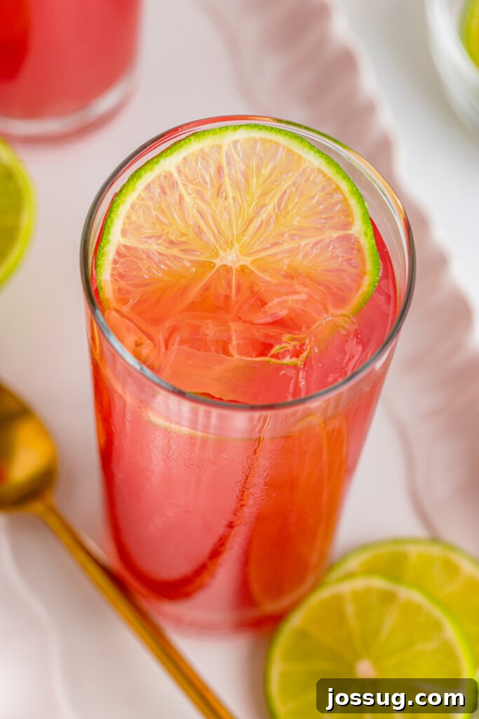Coastal Sunset Sipper 3 Overhead view looking down into a glass showcasing the vibrant layers of a Bay Breeze cocktail, with a lime wedge garnish.