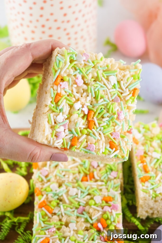 A hand holding a perfectly formed Easter Rice Crispy Treat, showcasing its fluffy texture and colorful sprinkles.