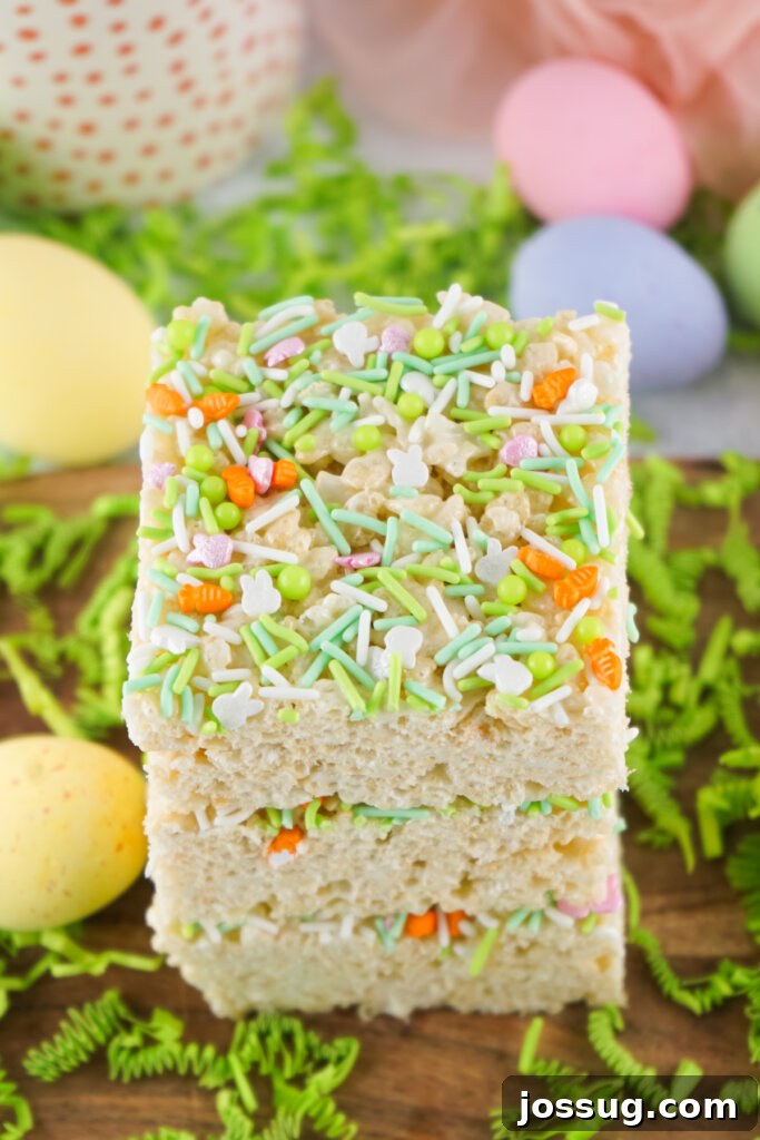 Three perfectly stacked Easter Rice Crispy Treats, each generously coated with colorful sprinkles, against a light background.