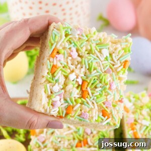 Hand holding an Easter Rice Crispy Treat decorated with festive sprinkles.