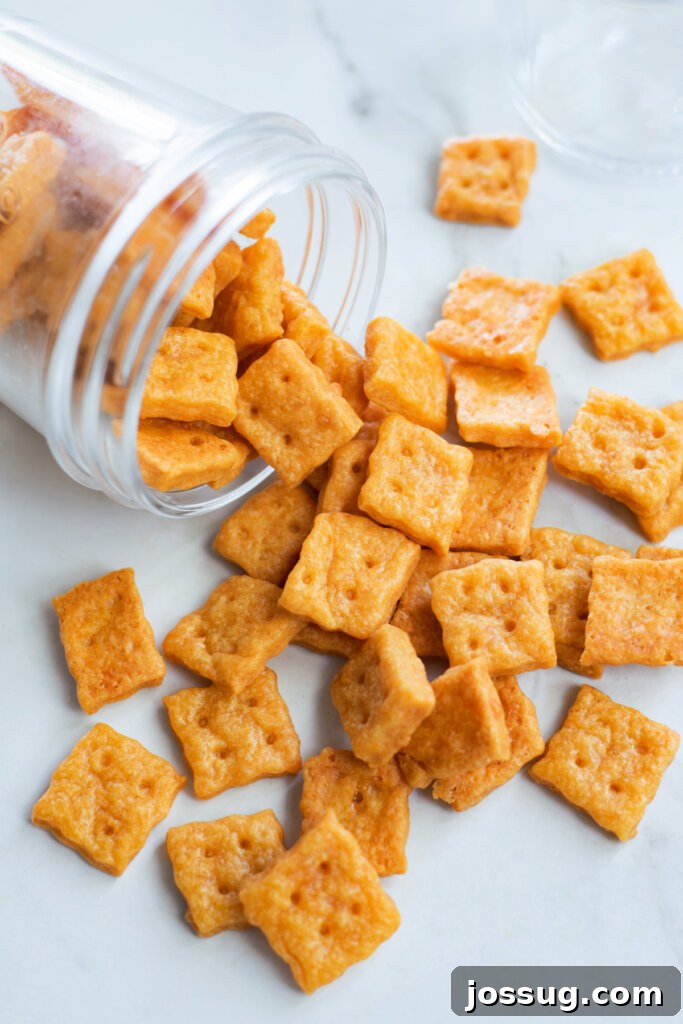 Cheesy Bites 2 Homemade cheese crackers spilling out of a clear glass jar, tempting and ready to eat.