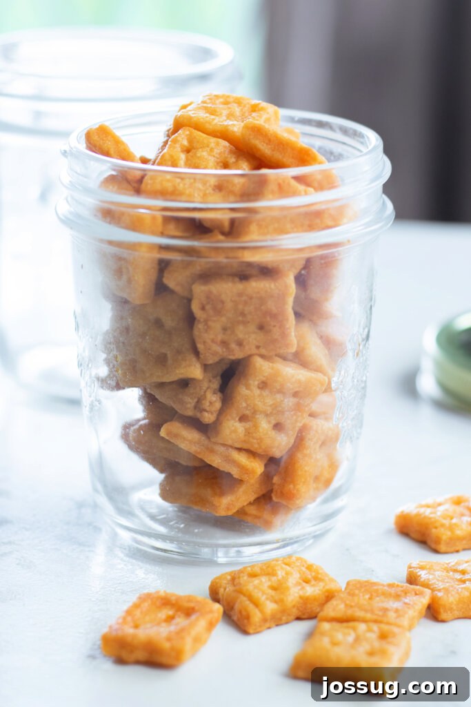 Cheesy Bites 4 Close-up of golden brown homemade cheese crackers stacked neatly in a glass jar.