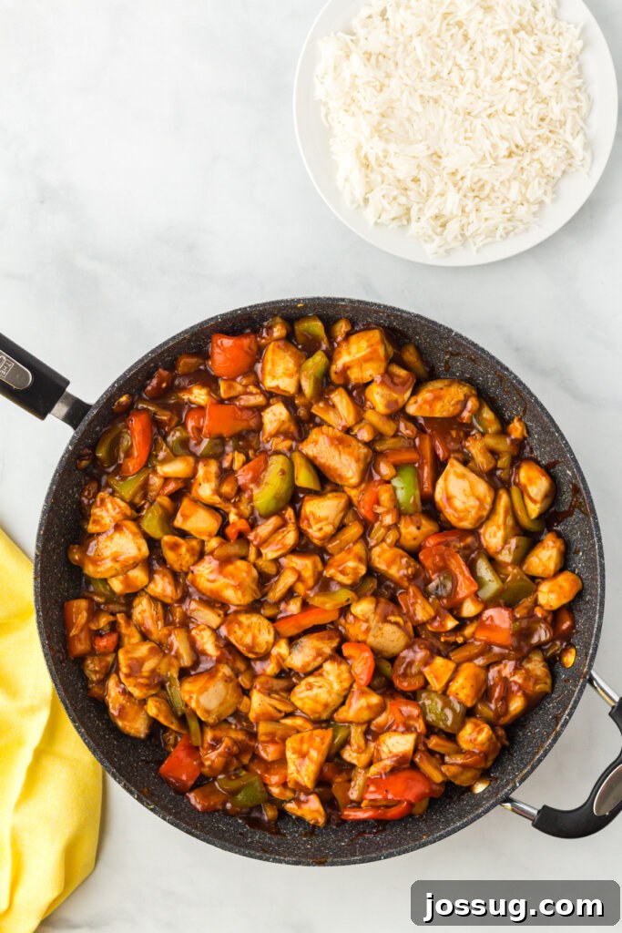 Sizzling Hawaiian Chicken, bell peppers, and pineapple cooking together in a large skillet, coated in a rich tropical sauce.
