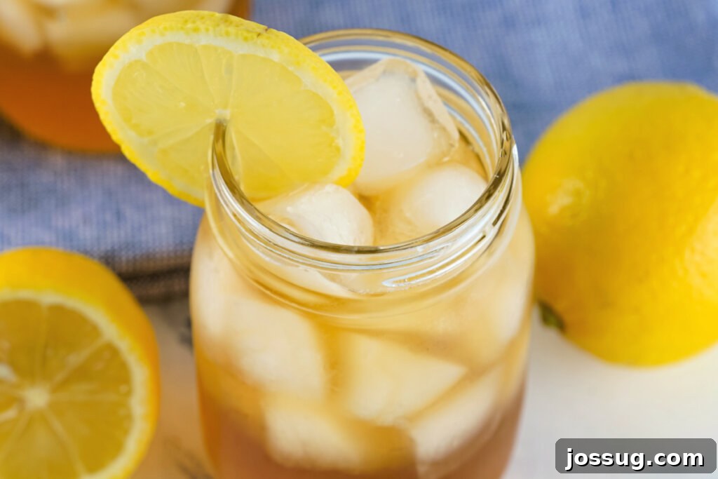 Overhead view looking into a glass of Spiked Arnold Palmer cocktail with ice and lemon slices, ready to be enjoyed.