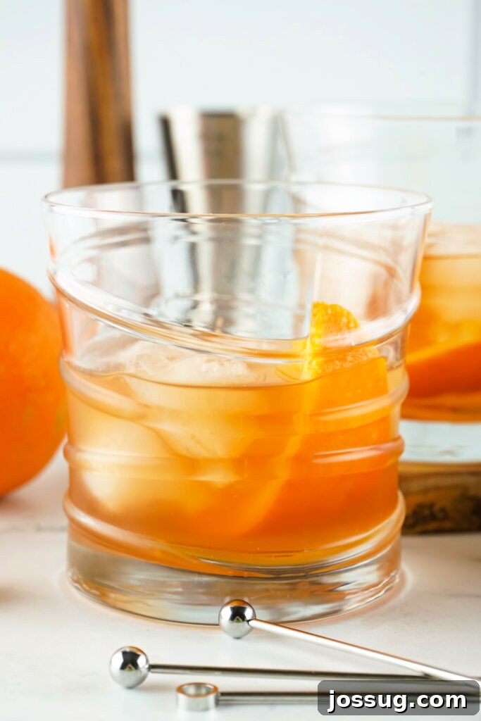 two old fashioned cocktails in glass with stirrers in front