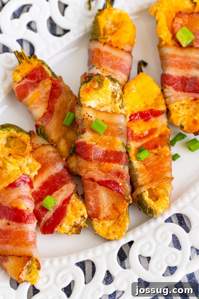 Bacon-Wrapped Jalapeno Poppers on a white plate, garnished and ready to serve