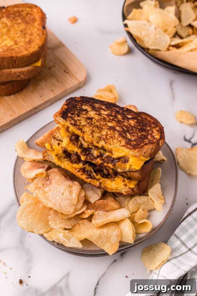 Sloppy Joe Meltdown 4 A finished Sloppy Joe Grilled Cheese sandwich served on a plate with potato chips, showcasing its golden crust and delicious filling.