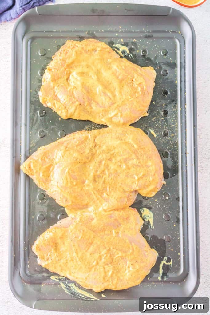 Juicy chicken breasts fully coated in a vibrant honey mustard marinade, neatly arranged on a tray, absorbing all the sweet and tangy flavors.