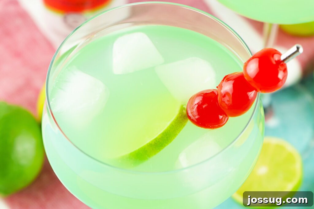 Marine Dream Elixir 5 Mermaid punch garnished with a lime slice and maraschino cherries in an elegant glass.