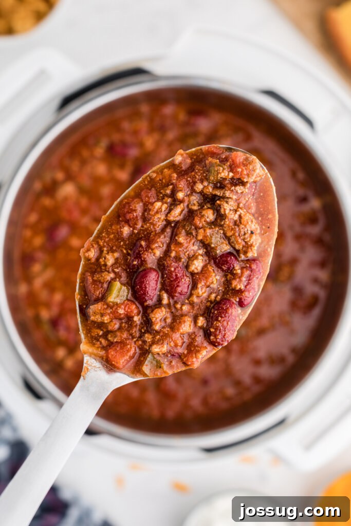Quick-Fix Instant Pot Chili 2 A spoonful of rich, red chili being lifted from an Instant Pot, showcasing its thick texture and vibrant color.
