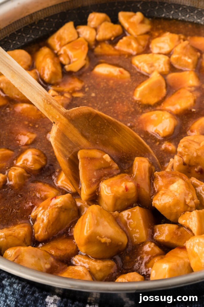 Velvet Bourbon Chicken 3 Sizzling Bourbon Chicken pieces cooking in a large skillet, coated in a rich, dark sauce.