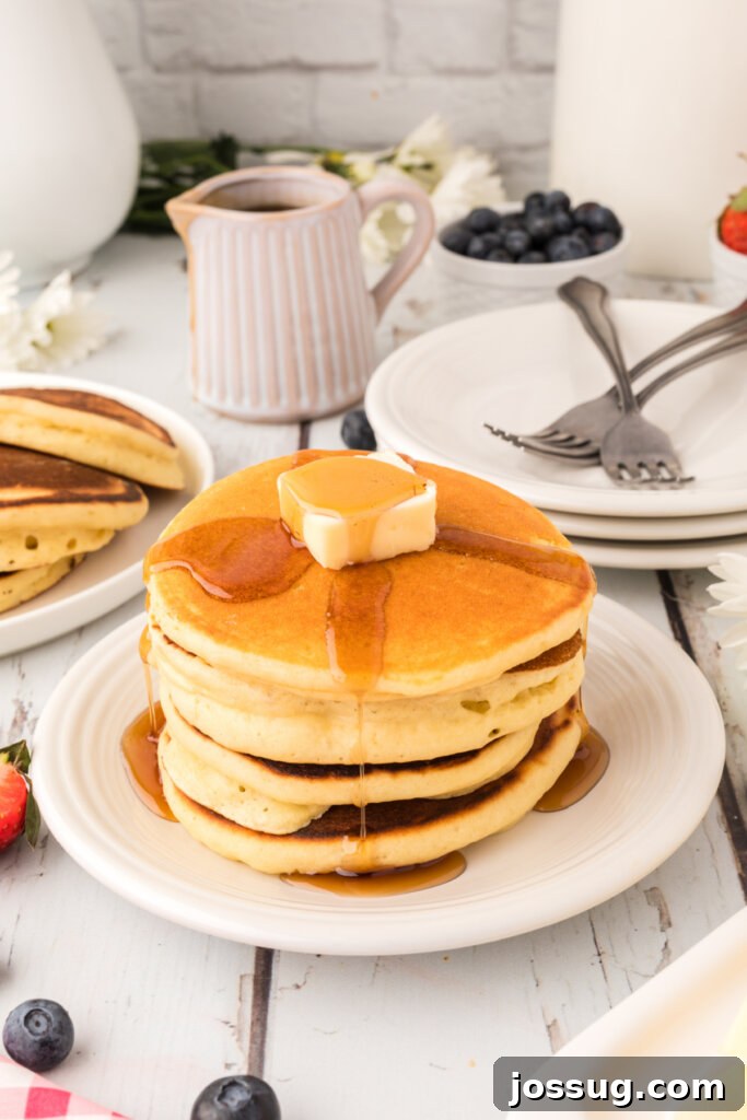 Stack of golden brown fluffy buttermilk pancakes with a dusting of powdered sugar