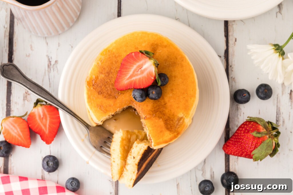 A beautifully arranged plate of buttermilk pancakes, glistening with syrup and a melting pat of butter
