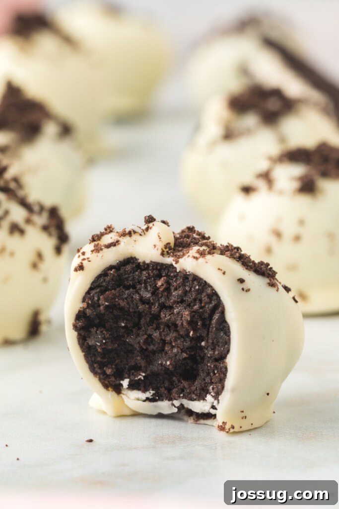 Close-up shot of an Oreo truffle, cut in half to reveal its creamy, cookie-filled interior and crisp candy coating.