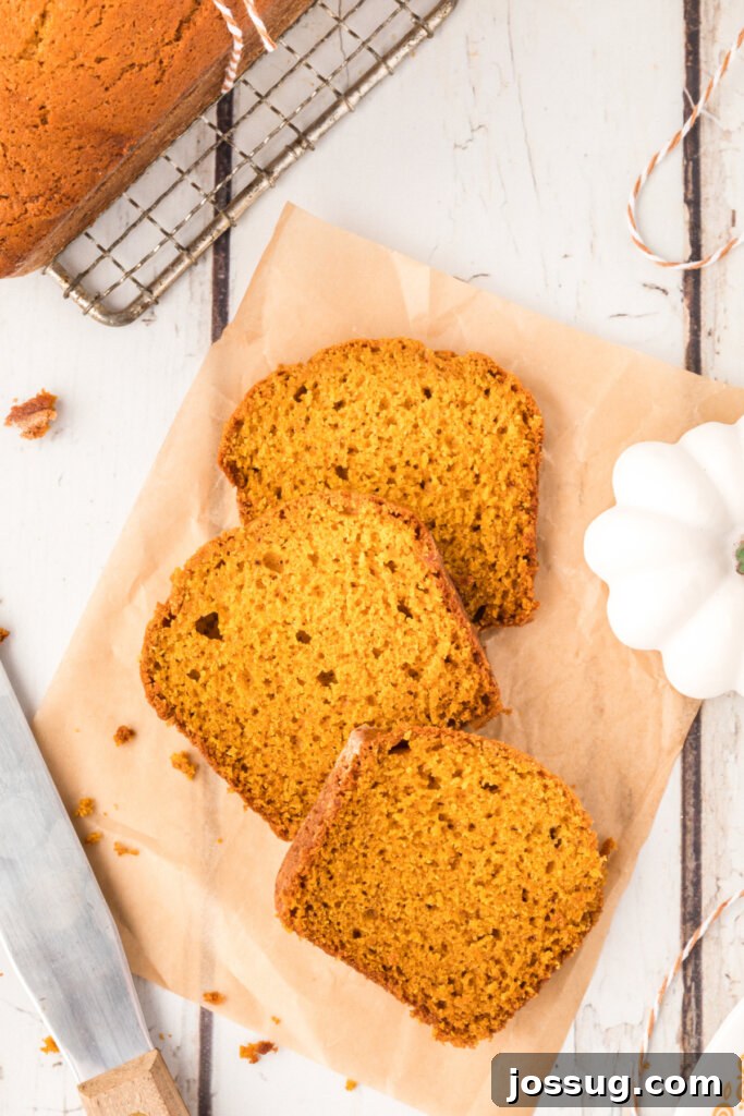 Cozy Pumpkin Spice Bread 4 Overhead view of three slices of pumpkin bread on a wooden board, showcasing their texture.